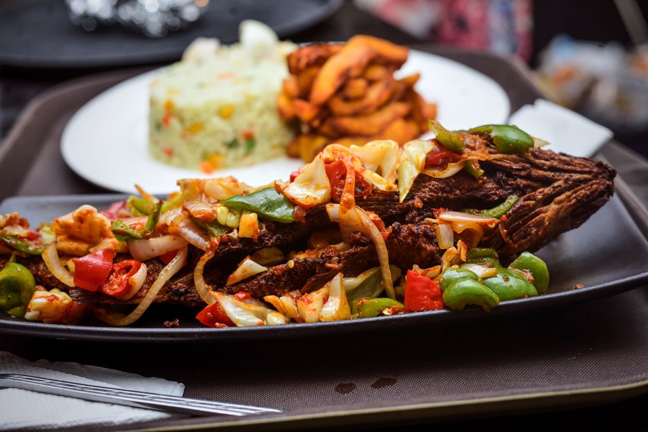 Delicious grilled fish topped with vegetables, served with rice and sides for a perfect meal.
