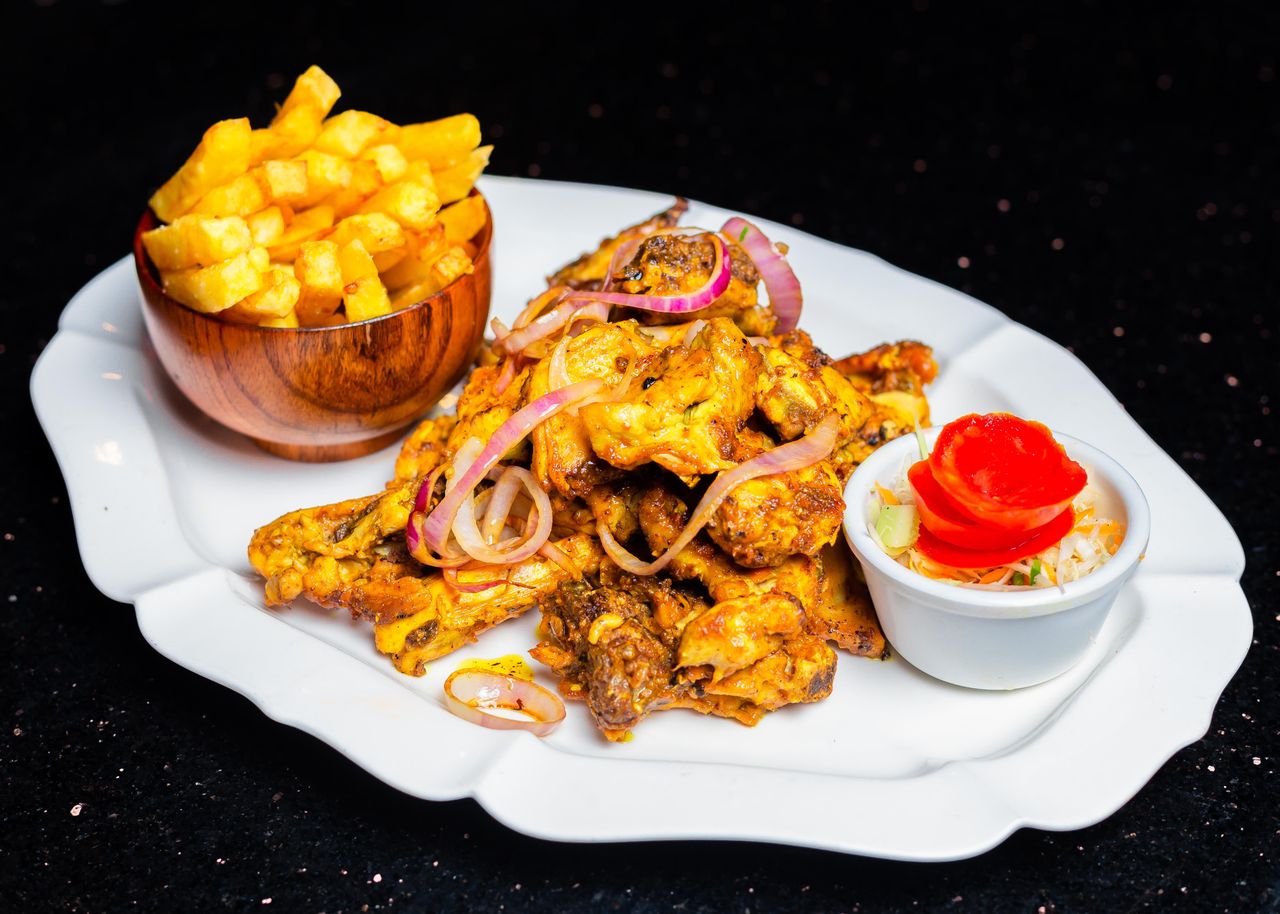 Savor spicy chicken wings with crispy fries and a fresh salad on a stylish plate.
