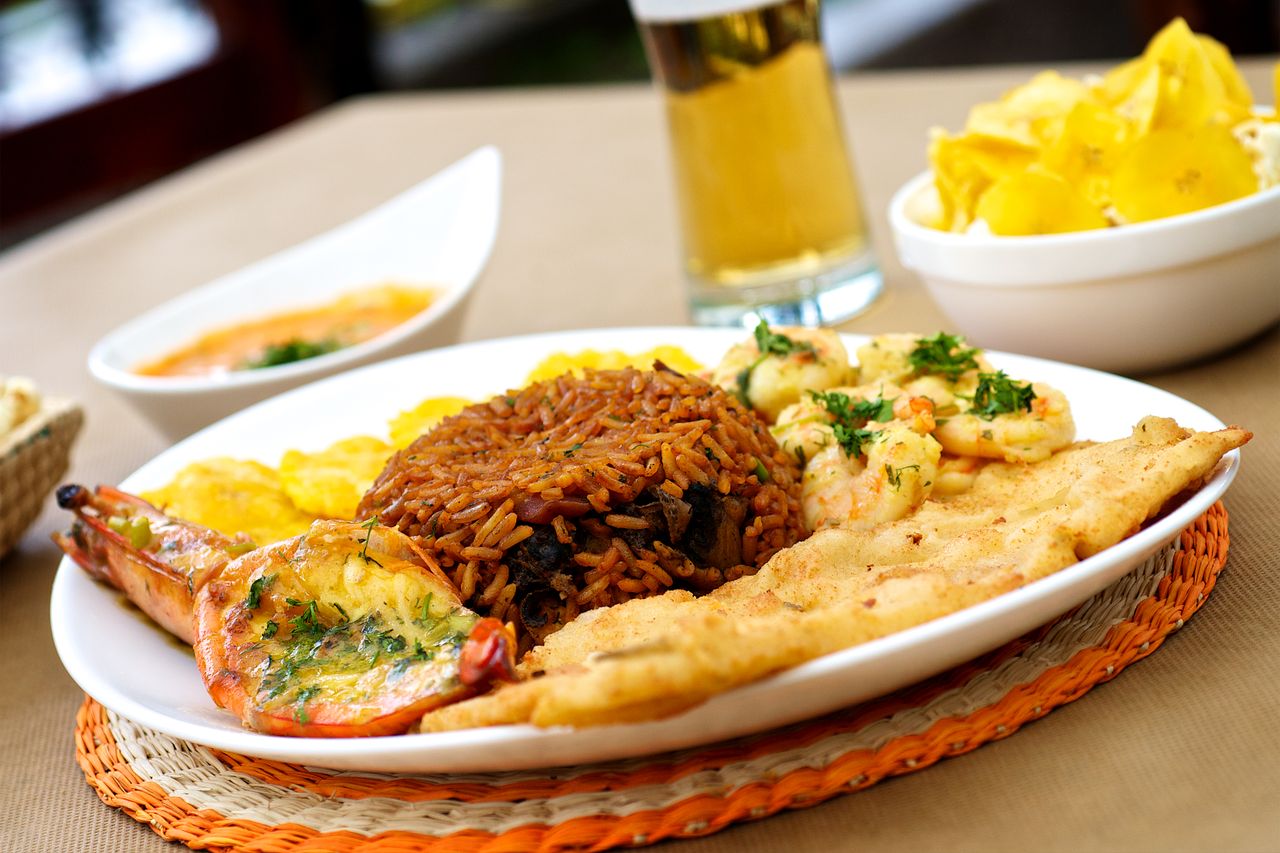 A vibrant seafood platter with fried rice, plantains, and a refreshing drink, perfect for a tropical meal.
